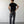 Load image into Gallery viewer, Man wearing a black t-shirt and dark pants standing against a plain white wall.
