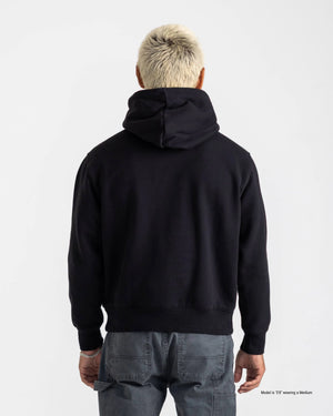 Short man shown from the back wearing a black Popover Hoodie and dark pants against a white background.
