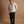 Load image into Gallery viewer, A short male model wearing a tan flannel button-up shirt, dark pants, and black sneakers against a warm brown studio backdrop.
