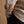 Load image into Gallery viewer, A close-up of a tan flannel shirt worn by a short male model, highlighting the textured fabric, curved hem, and buttoned cuff.
