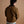 Load image into Gallery viewer, A man shown from the back wearing a brown jacket with a black collar, blue jeans, and a white undershirt, set against a solid warm brown studio background.
