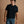 Load image into Gallery viewer, A man wearing a black short-sleeve crewneck t-shirt and blue jeans, standing against a solid warm brown studio background.

