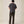 Load image into Gallery viewer, A man viewed from behind wearing a dark charcoal gray short-sleeve t-shirt and dark olive brown pants, standing against a solid light beige studio background.
