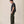 Load image into Gallery viewer, A man stands in profile wearing a dark charcoal gray short-sleeve T-shirt, olive green trousers, and white sneakers against a plain beige studio background.
