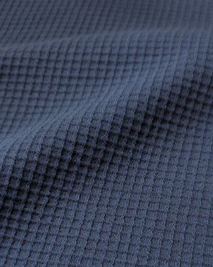 Short Man wearing a blue textured waffle shirt against a plain background