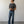 Load image into Gallery viewer, Man wearing a dark gray t-shirt and blue jeans standing against a plain white wall.
