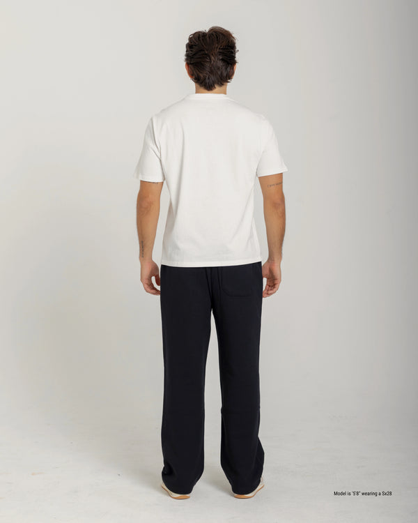 Short man wearing a white shirt and black pants on a plain background