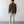 Load image into Gallery viewer, Man wearing a brown shirt and beige pants standing against a plain white wall.
