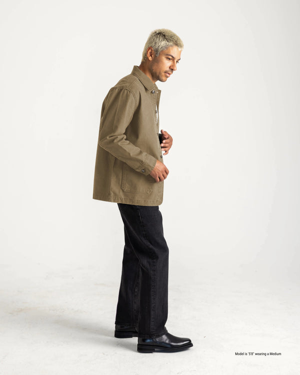 Man wearing a beige jacket and black pants on a white background