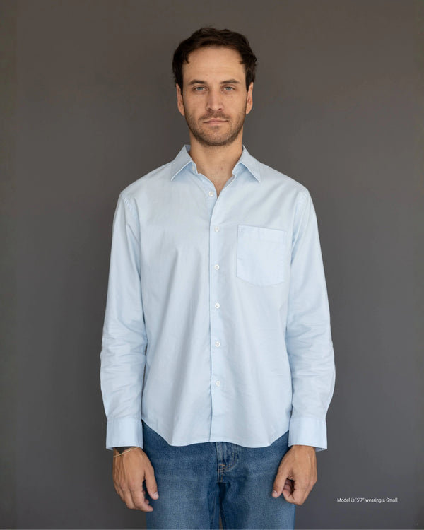 Man under 5'10 wearing a light blue shirt and jeans against a gray background