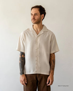 Man wearing a beige short-sleeve shirt against a plain background