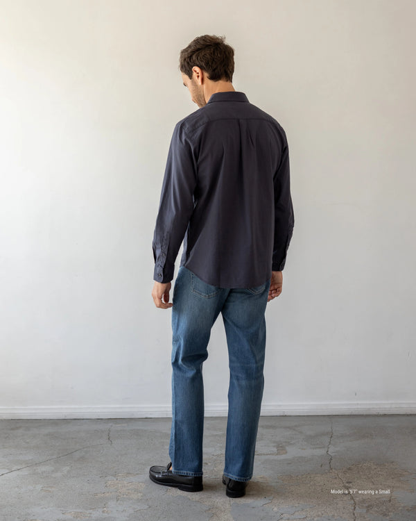 5'7" Man wearing a dark shirt and blue jeans standing against a plain white wall.