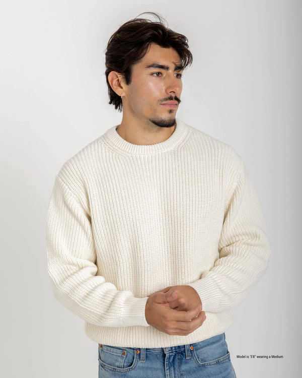 Short Man wearing a cream sweater and blue jeans against a white background
