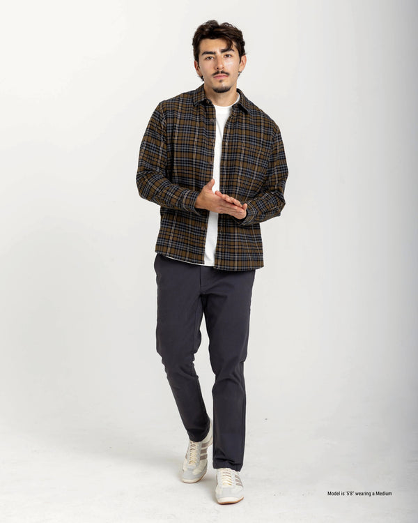 Man wearing a plaid shirt and dark pants on a white background