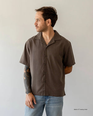 Man wearing a beige short-sleeve shirt against a plain background