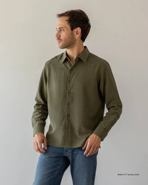 Short Man wearing an olive green shirt and blue jeans against a plain background