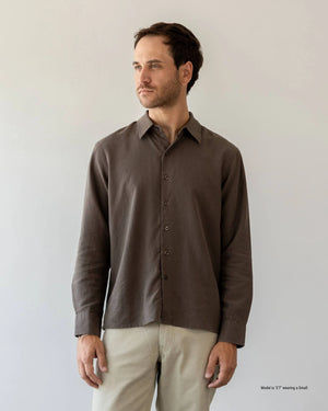 Short Man wearing an olive green shirt and blue jeans against a plain background