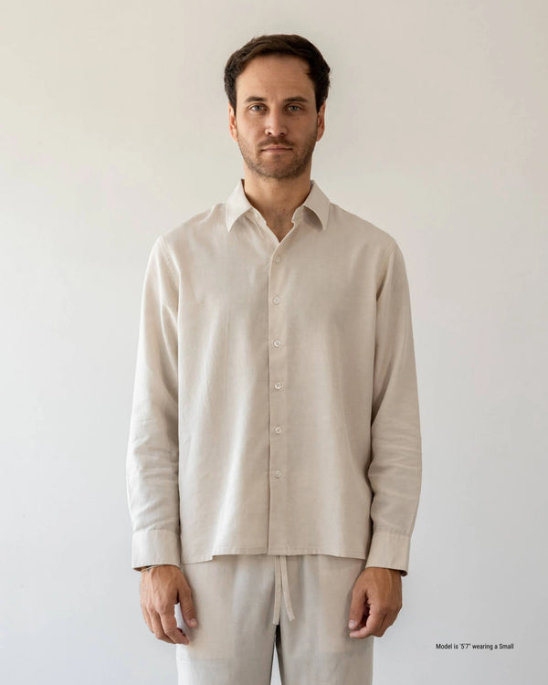 Man wearing a beige shirt and pants against a plain background