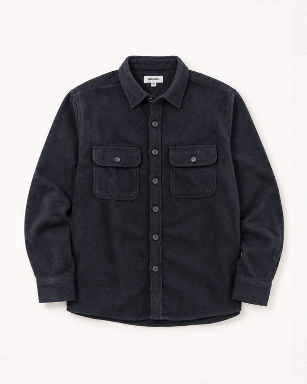 A dark navy textured button-up shirt jacket with two buttoned chest pockets, laid flat against a light off-white background.