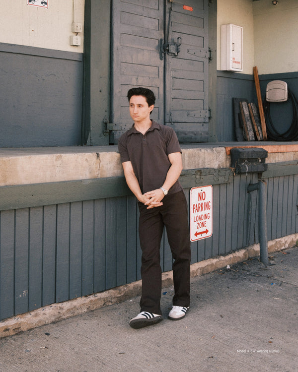 5'4" Man leaning against a wall with a 'No Parking' sign in the background