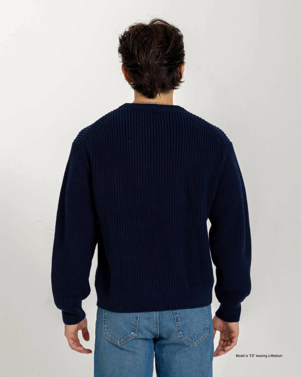 Short Guy wearing a navy blue sweater and light blue jeans on a white background