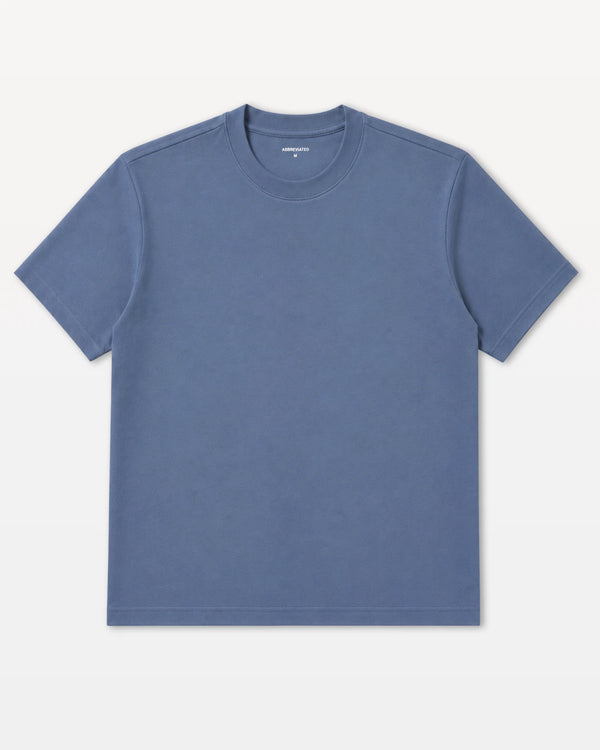 A classic short-sleeve crewneck t-shirt in a muted slate blue color, laid flat against a clean off-white background.