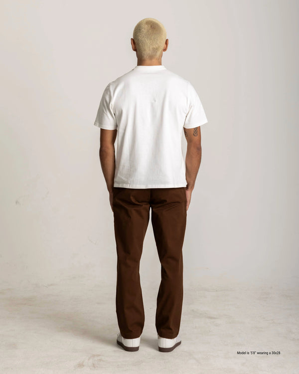 Person wearing a white t-shirt and brown pants on a plain background