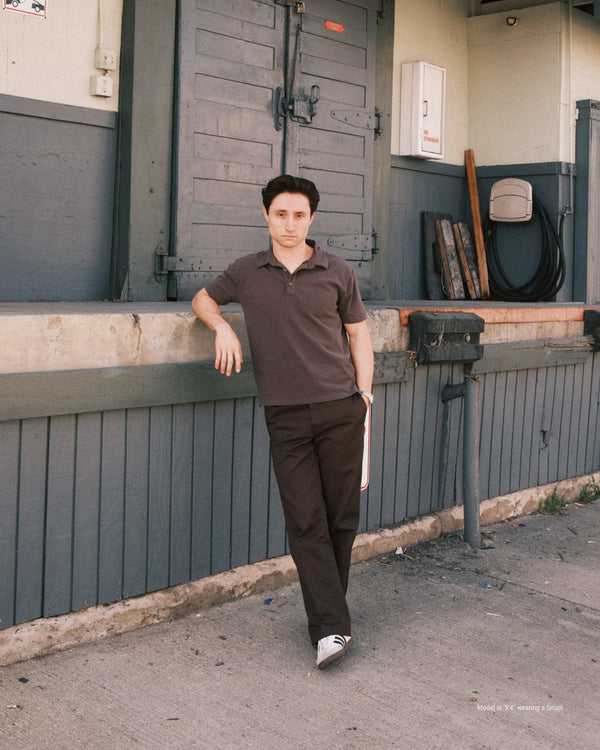 5'4" Man standing against a gray wall with a door in an urban setting