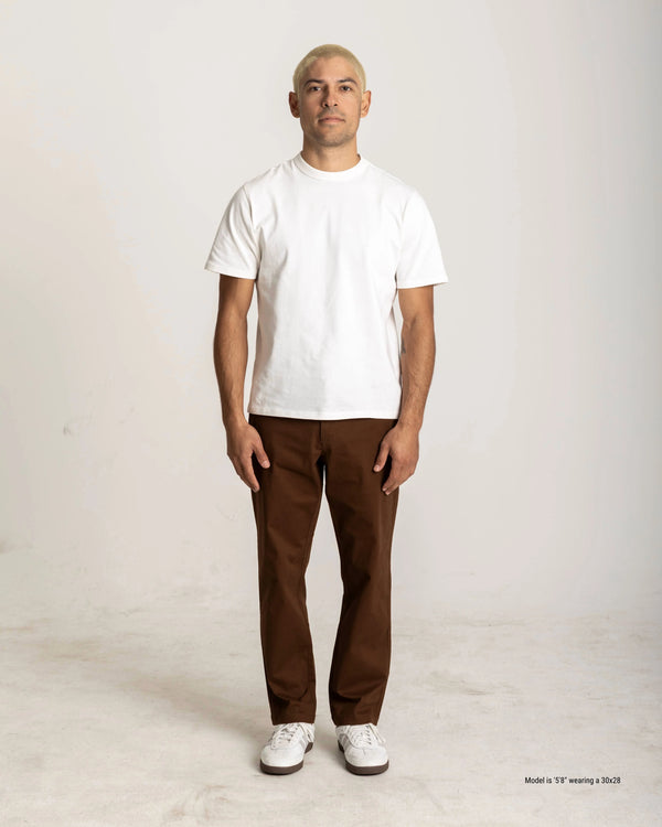 Person wearing a white t-shirt and brown pants on a plain background