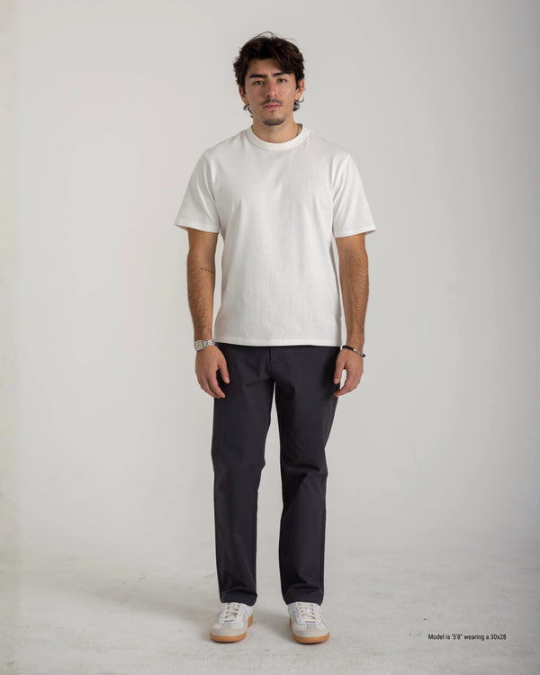 Man wearing a white t-shirt and dark pants on a plain background