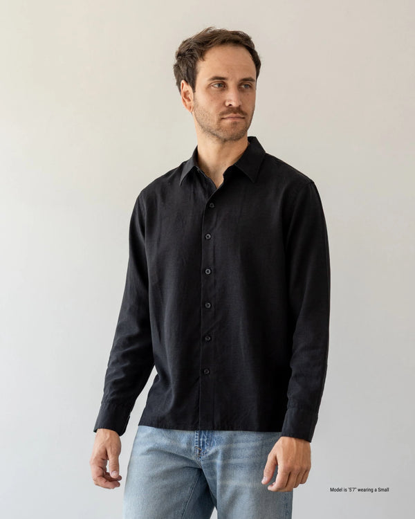 Man wearing a black shirt and jeans against a plain background