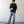 Load image into Gallery viewer, Man wearing a black shirt and light blue jeans standing against a white wall.
