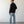 Load image into Gallery viewer, Man wearing a black shirt and light blue jeans standing against a white wall.
