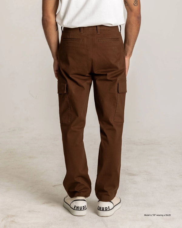 Person wearing brown cargo pants and white sneakers on a plain background