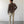 Load image into Gallery viewer, Man wearing a brown shirt and beige pants standing against a white wall.
