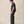 Load image into Gallery viewer, A man stands in profile wearing a dark charcoal gray short-sleeve T-shirt, olive green trousers, and white sneakers against a plain beige studio background.
