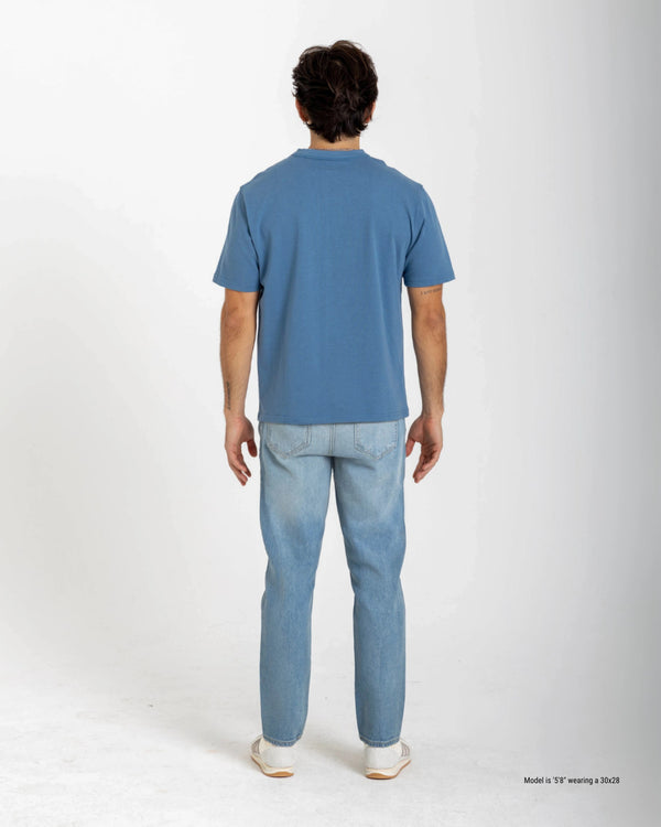 Short Person wearing a blue t-shirt and light blue jeans on a white background