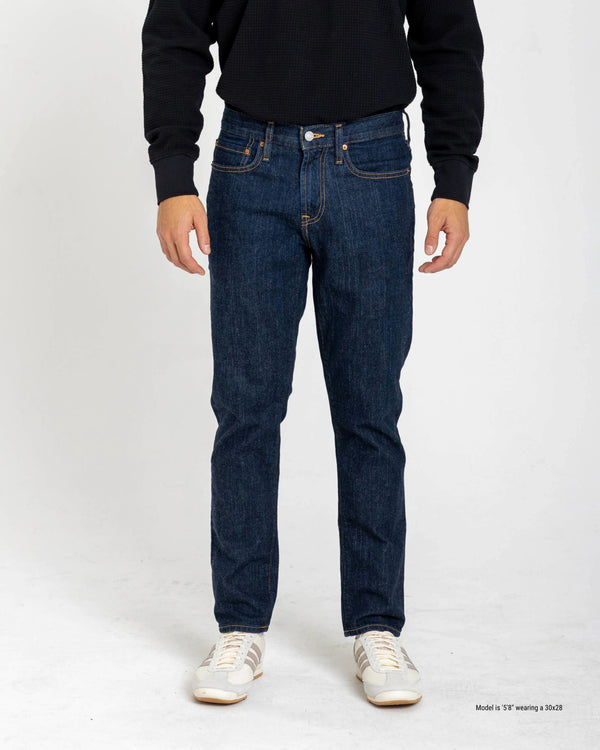 Shorter Person wearing dark blue jeans and a black shirt on a white background