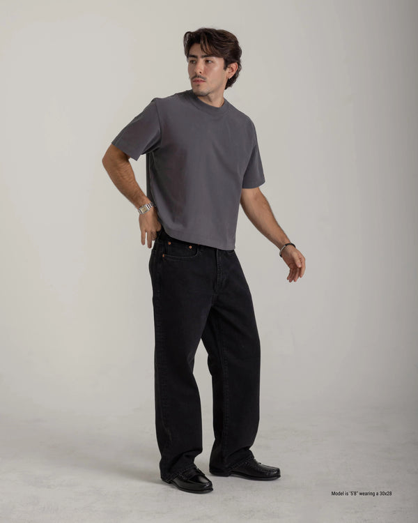 Man wearing a gray t-shirt and black pants on a plain background