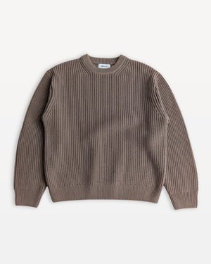 Shorter Man wearing a navy blue sweater and jeans against a white background