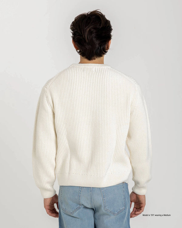 Short Person wearing a white sweater and light blue jeans on a plain background