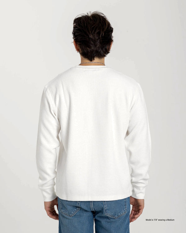 Person wearing a white long-sleeve shirt and blue jeans on a plain background