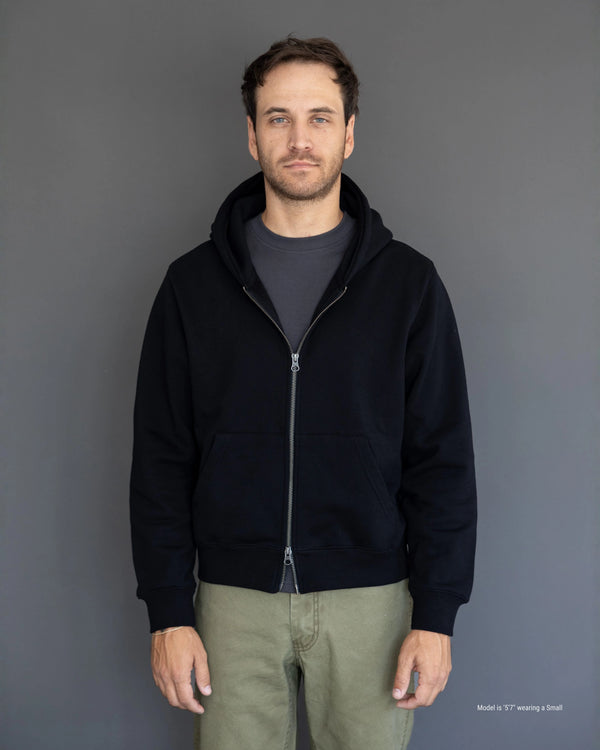 Short Man wearing a black hoodie against a gray background